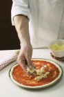 Chef polvilhando pizza com queijo — Fotografia de Stock