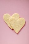 Vista de cerca de dos corazones de pastelería en la superficie rosa - foto de stock