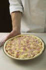 Шеф-повар держит невыпеченную пиццу — стоковое фото