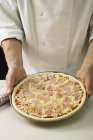 Koch hält ungebackene Pizza in der Hand — Stockfoto