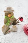 Vista de primer plano de pastelería especiada muñeco de nieve en harina con bolas de Navidad - foto de stock