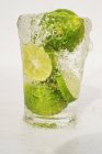 Limes fatiados em vidro de água — Fotografia de Stock