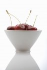 Four cherries in white bowl — Stock Photo