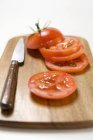Tranches de tomate et couteau — Photo de stock