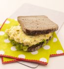 Sandwich aux œufs brouillés sur serviettes sur planche à découper — Photo de stock