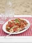Closeup view of chicken and red pepper salad with glasses and bottle — Stock Photo