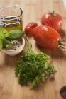 Ingredientes para la salsa de tomate: tomates, hierbas, aceite de oliva, especias sobre la superficie de madera - foto de stock