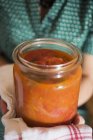 Жінка тримає консервовану банку томатного соусу в руках, середній розтин — стокове фото