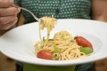 Mujer comiendo espaguetis con tomates - foto de stock