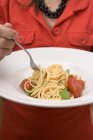 Mulher comendo espaguete com tomate — Fotografia de Stock
