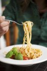 Mujer comiendo espaguetis con tomates - foto de stock