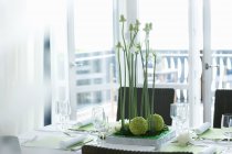 Laid dining table with flower arrangement, light balcony behind — Stock Photo