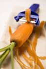 Descascando cenoura com descascador de vegetais — Fotografia de Stock