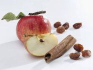 Apple with cinnamon stick and raisins — Stock Photo