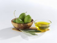 Aceitunas verdes con hojas de oliva y aceite - foto de stock