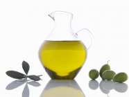 Olive oil in carafe with green olives — Stock Photo