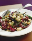 Bean salad with grilled onions on white plate with fork — Stock Photo