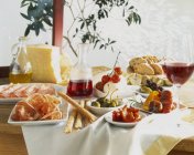 Стол накрыт антипасти и красным вином — стоковое фото