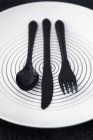 Крупный план черных пластиковых столовых приборов на тарелке — стоковое фото