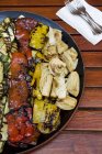 Grilled vegetables on black platter over wooden surface — Stock Photo