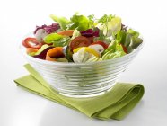 Mixed salad in a glass bowl over green towel — Stock Photo