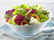 Colourful mixed salad in a glass bowl over towel — Stock Photo