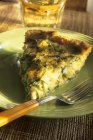 Slice of Zucchini Quiche on green plate with fork — Stock Photo