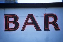 Daytime view of neon bar sign on white building wall — Stock Photo
