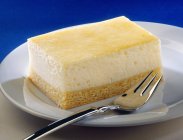 Tranche de gâteau au fromage sur une assiette avec fourchette — Photo de stock