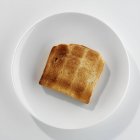 Nahaufnahme von oben mit einer Scheibe Toast auf einem weißen Teller — Stockfoto