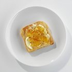 Крупный план тоста с маслом и мармеладом на тарелке — стоковое фото