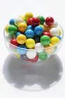 Vista de cerca de bolas de goma de mascar de colores en tazón de vidrio - foto de stock