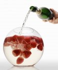 Pouring sparkling wine into strawberry punch — Stock Photo