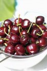 Fresh cherries in sieve — Stock Photo