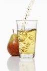 Verter jugo de pera en un vaso - foto de stock