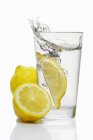 Cunha de limão caindo em vidro — Fotografia de Stock