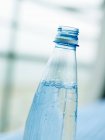 Vista de perto de água mineral em garrafa de plástico aberta — Fotografia de Stock