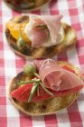 Crostini with raw ham and giant capers — Stock Photo