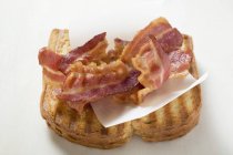 Rayures de bacon frit sur du pain grillé — Photo de stock