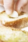 Hand Filling baguette slice with garlic — Stock Photo