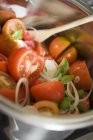 Ensalada de tomate con cebolla y albahaca en un tazón de metal con cuchara de madera - foto de stock