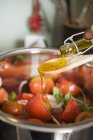 Pouring olive oil over tomato salad — Stock Photo