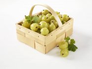 Fresh gooseberries in wooden basket — Stock Photo