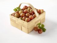 Fresh gooseberries in wooden basket — Stock Photo