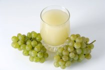 Glass of juice and bunches of grapes — Stock Photo