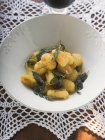 Closeup view of Gnocchi with sage in white bowl on doily — Stock Photo
