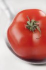 Red tomato on spoon — Stock Photo