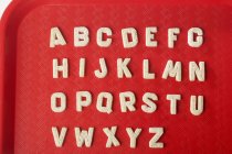Vue rapprochée des cookies alphabet sucre sur plateau en plastique rouge — Photo de stock