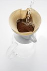 Heißes Wasser auf gemahlenen Kaffee gießen — Stockfoto