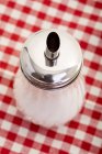 Vista close-up de um pourer de açúcar em uma toalha de mesa quadriculada — Fotografia de Stock